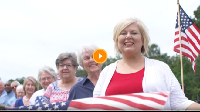 Video thumbnail of a woman smiling with an American flag in the background.